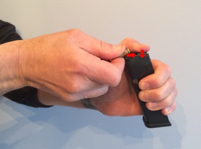 Use your strong hand and begin to insert a cartridge into the magazine while simultaneously pushing down on the spring with your thumb of the weak hand.